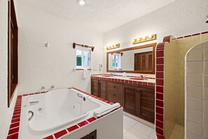 Une salle de bain avec une grande baignoire, un meuble-lavabo avec un miroir et un espace douche.