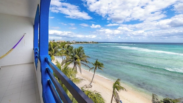 A balcony with a view of a beach and ocean. - Absolute Beachfront - 3 Bedroom Condominium at Del Sol (Akumal)
