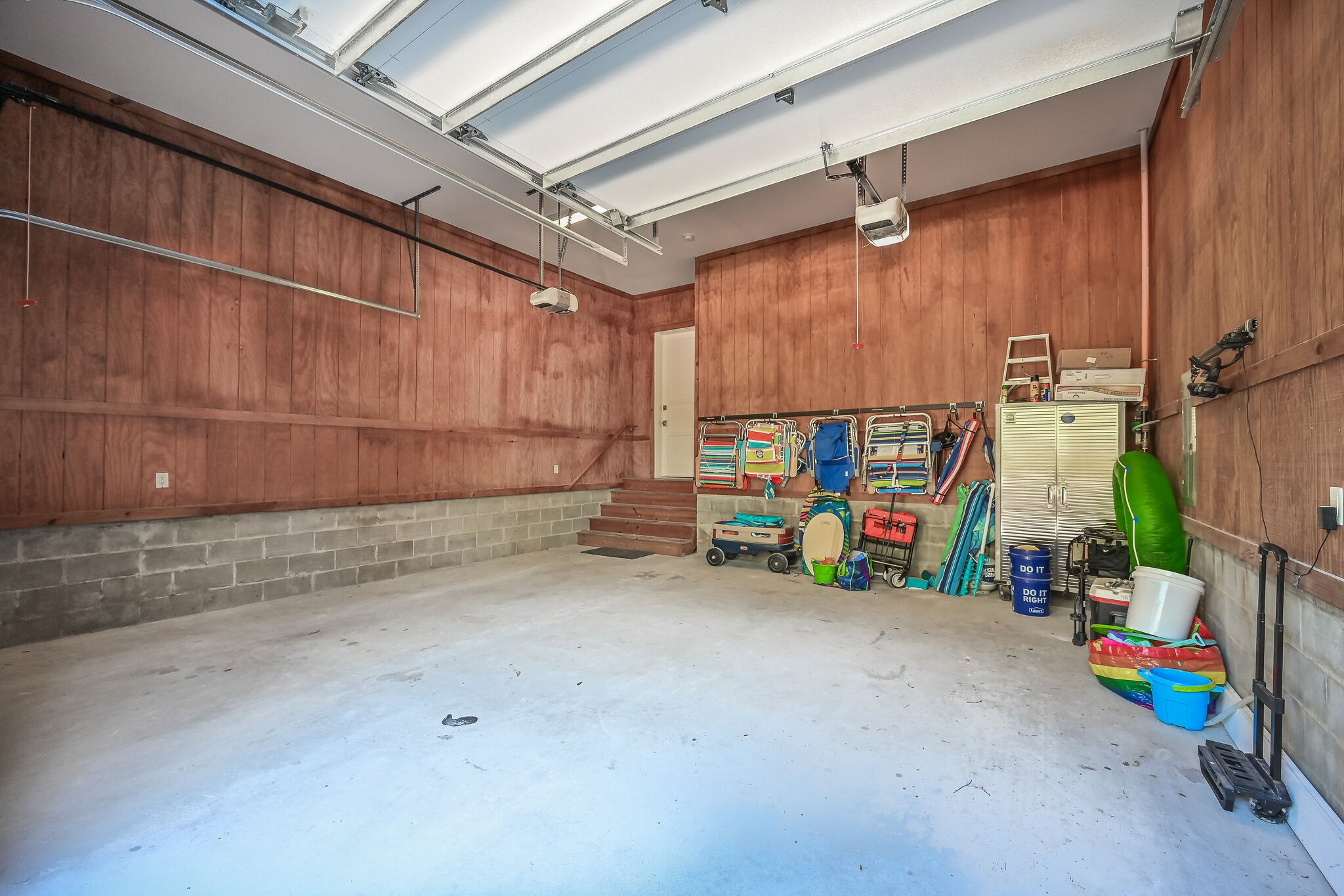 Een ruime garage met houten wanden, een betonnen vloer en diverse gereedschappen en apparatuur die langs de muren staan opgeslagen.