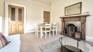 A dining area with a wooden table and chairs, a fireplace, and a mirror on the wall. - Henderson - New Town Apartment (Edinburgh)
