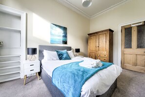 A bedroom with a bed, a wardrobe, a nightstand, and a painting on the wall.