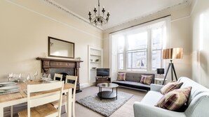 A living room with a dining table set, a sofa, a fireplace, and a television. - Henderson - New Town Apartment (Edinburgh)