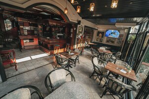 Um restaurante com mobiliário de madeira, um bar e uma tela de televisão.