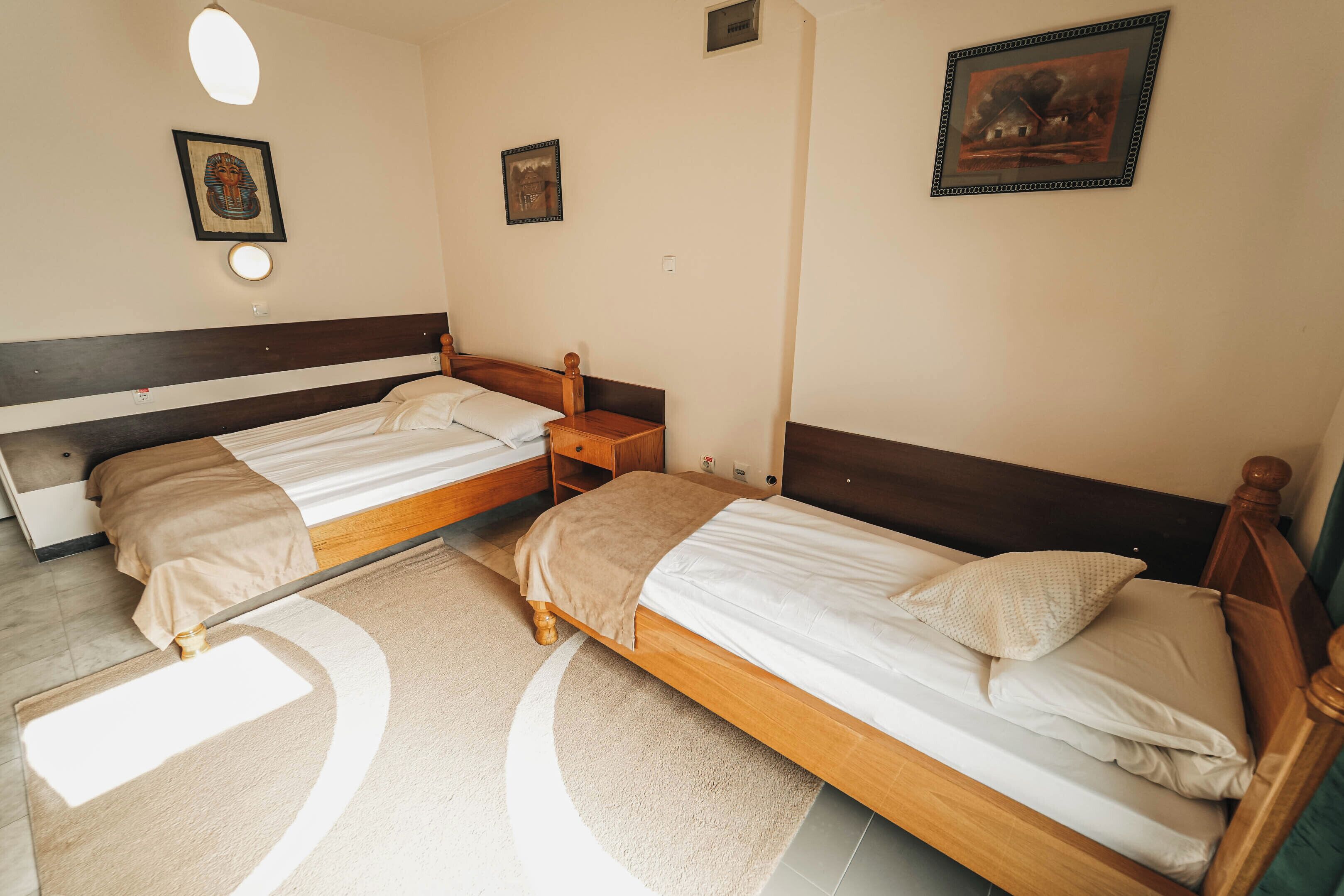 A bedroom with two single beds, a bedside table, and a nightstand.