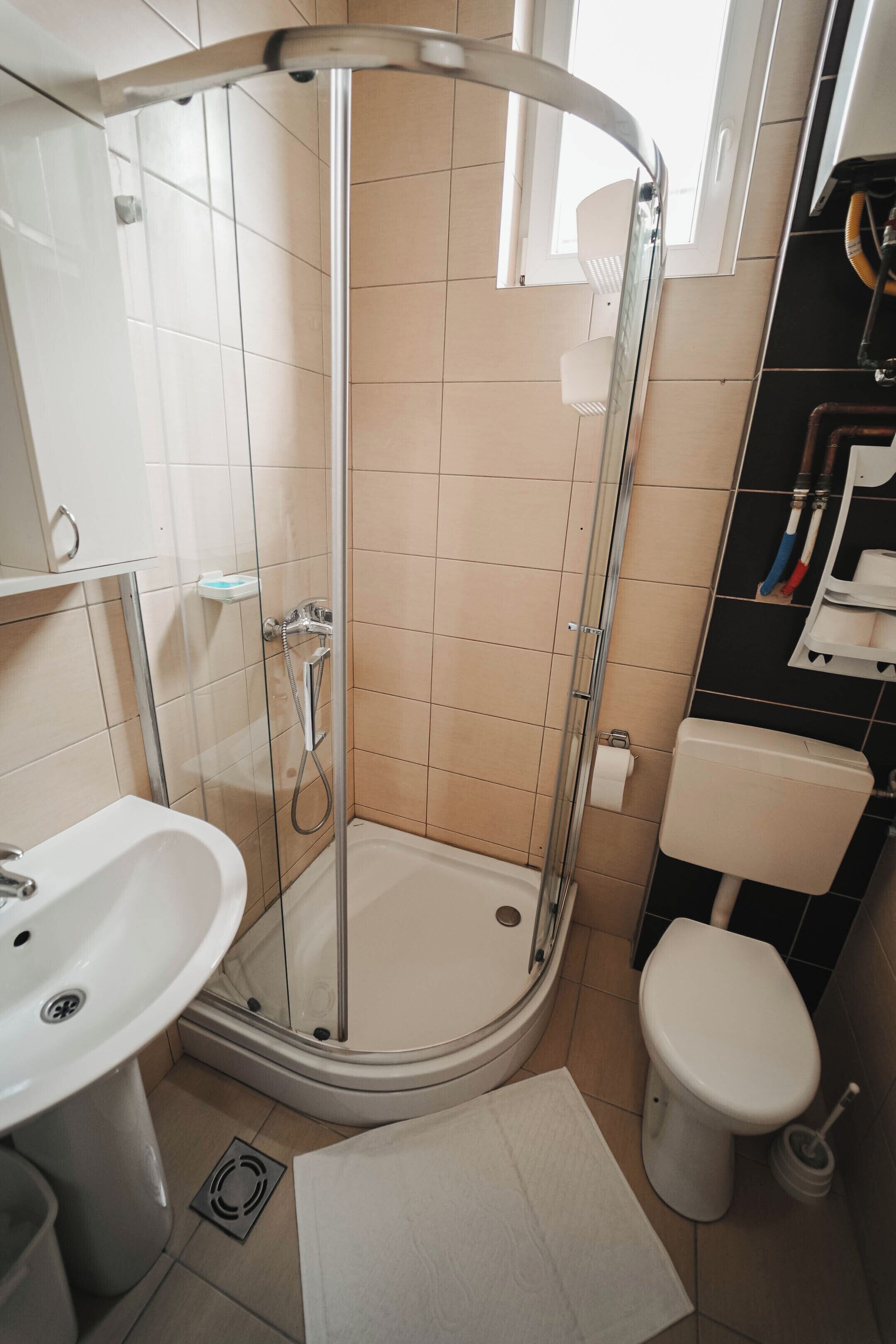 Une salle de bain avec une douche à parois de verre, un lavabo blanc et des toilettes.