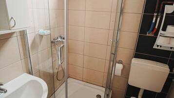 Une salle de bain avec une douche à parois de verre, un lavabo blanc et des toilettes.
