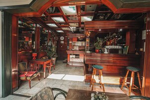 Uma área de bar com mobiliário de madeira, balcão e banquetas.