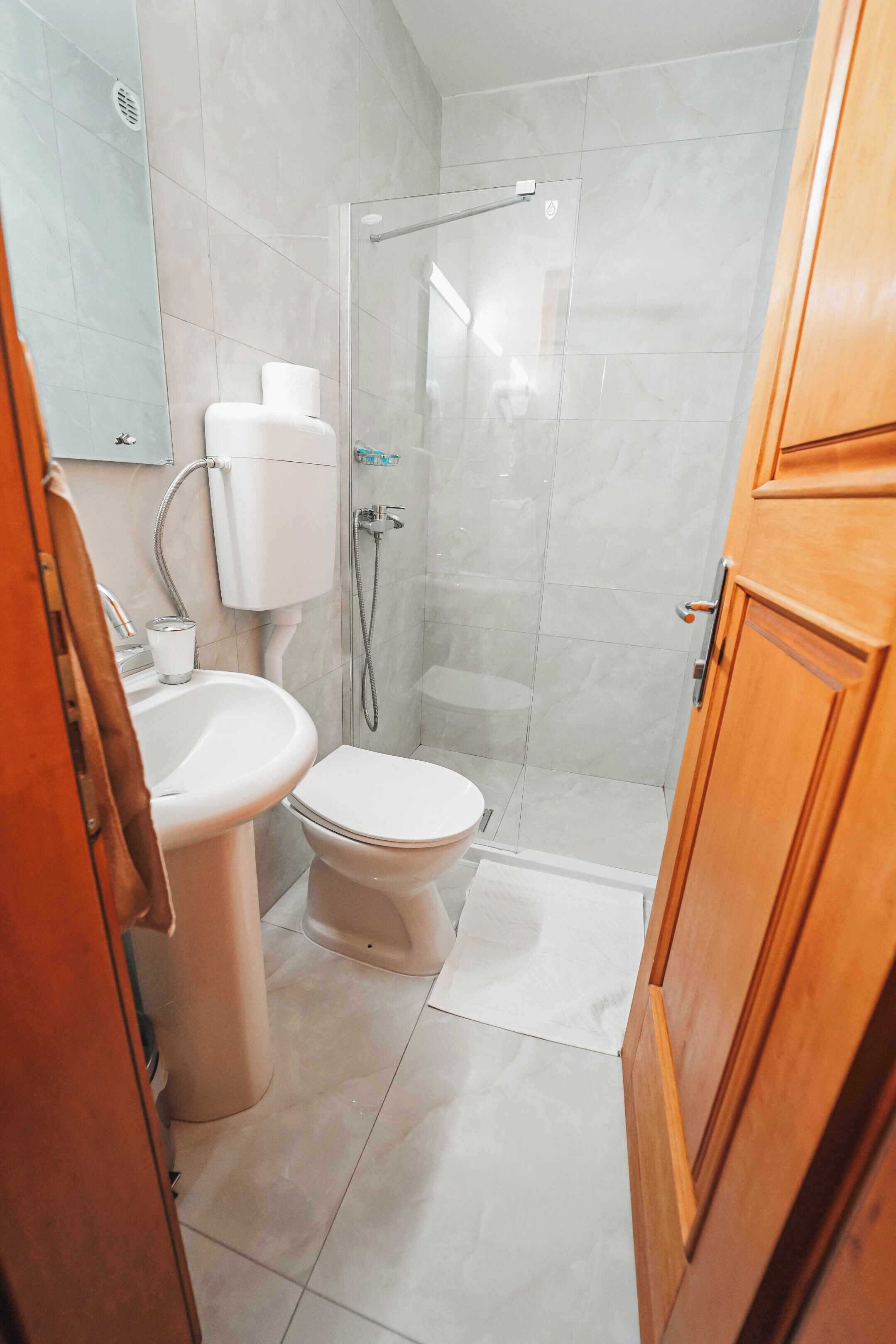 A bathroom with a toilet, sink, and shower.