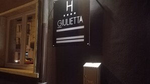 Et skilt med bogstavet 'H' og navnet 'GIULIETTA' på en væg, der angiver et hotel eller lignende sted.