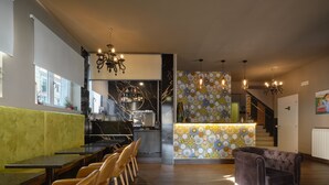 Et moderne køkken med marmor bagvæg, indbygget vinkøler og spiseområde med læderstole og en grøn sofa.