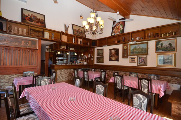 A restaurant with checkered tablecloths, wooden chairs, and various framed pictures on the walls. - Holiday Home Karalic (Ležimir)