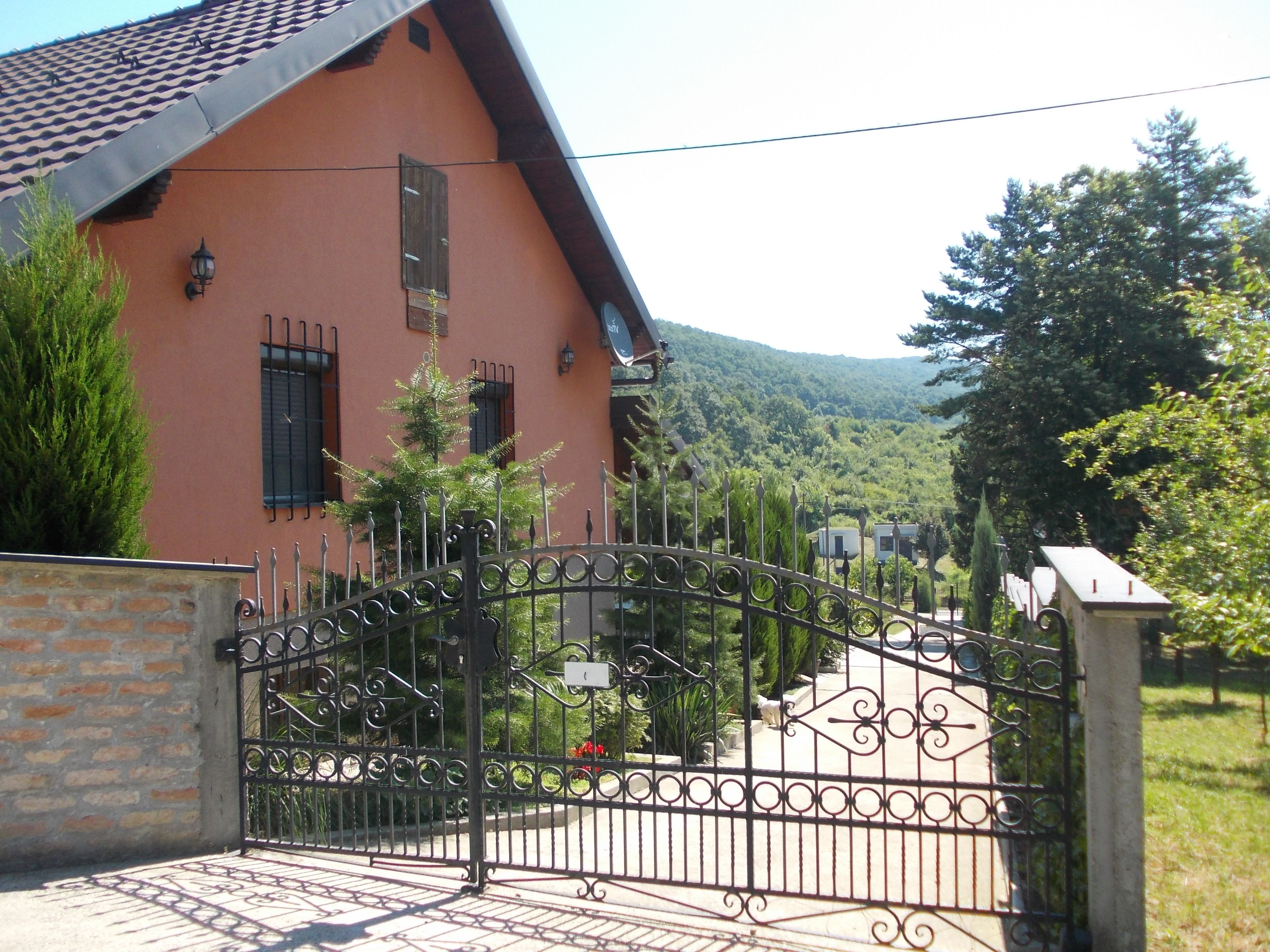 Ein Haus mit einem Metallgitter, einer Steinmauer und einem Berg im Hintergrund.