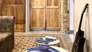 A cozy room with a wooden door, a guitar, a sofa, and a small table with books. - BirdHouse Valencia (Valencia)