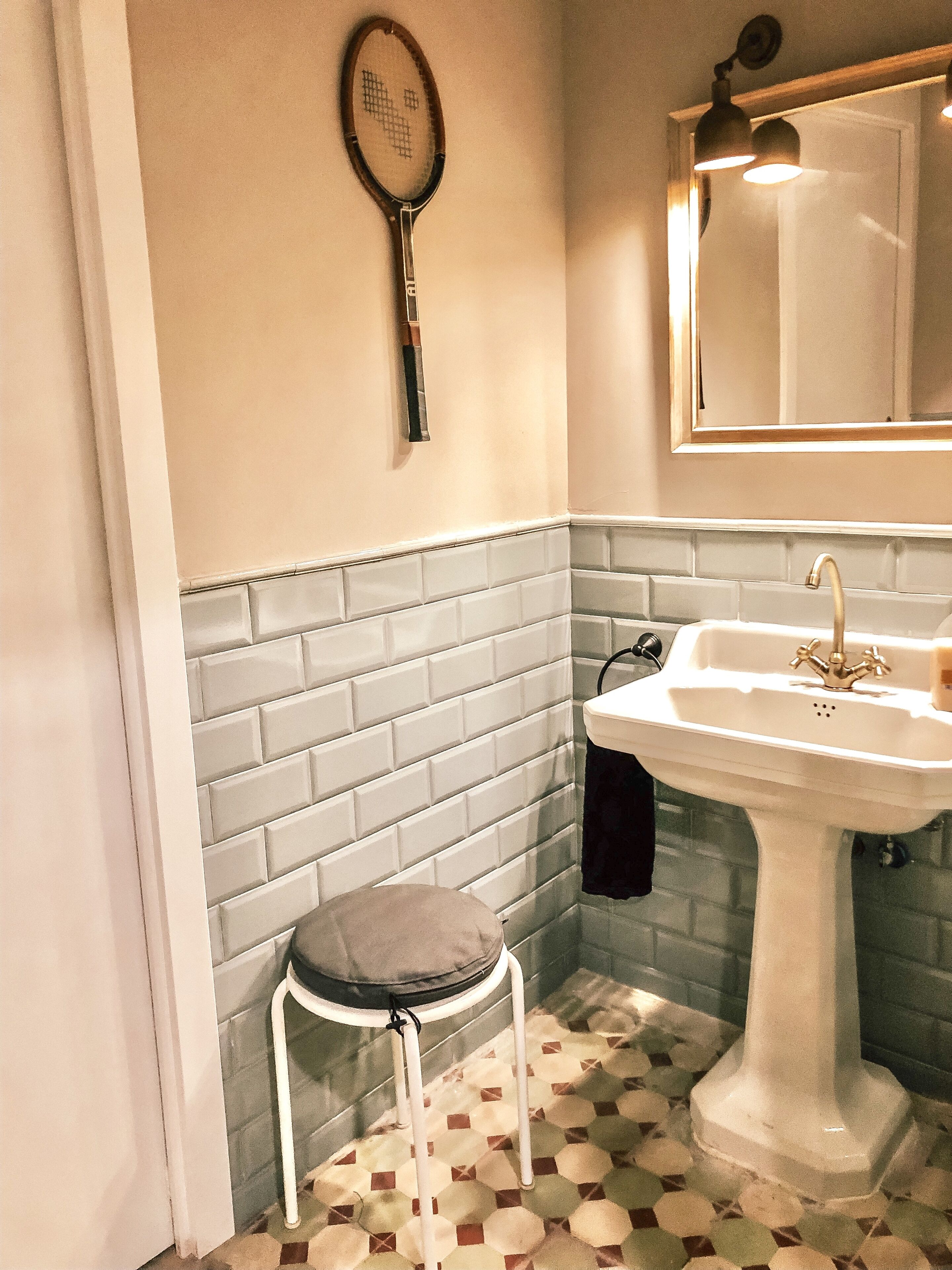 A bathroom with a white sink, a mirror above it, and a patterned floor.