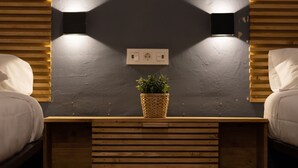 A bedroom with two beds, a bedside table with a plant, and wall-mounted lighting. - BirdHouse Valencia (Valencia)