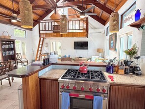 A kitchen with a central island, a stove, and a hanging light fixture.