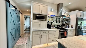 A modern kitchen with white cabinets, a stainless steel refrigerator, and a microwave. - Waterfront beauty with dock and fireplace! Check in Bay! New Hot Tub!! (Afton)