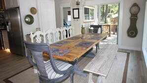 A dining area with a wooden table, white chairs, and a chandelier. - Waterfront beauty with dock and fireplace! Check in Bay! New Hot Tub!! (Afton)