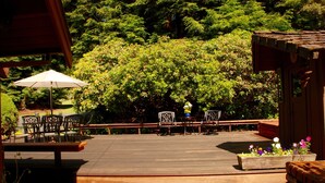 A wooden deck with outdoor furniture, surrounded by lush greenery and a wooden pergola. - Beautiful Home in the Heart of the Majestic Redwoods.  Secluded on 10 acres. (Fort Bragg)