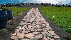 A stone pathway leading to a beach area with picnic tables and barrels. - Beautiful Home in the Heart of the Majestic Redwoods.  Secluded on 10 acres. (Fort Bragg)