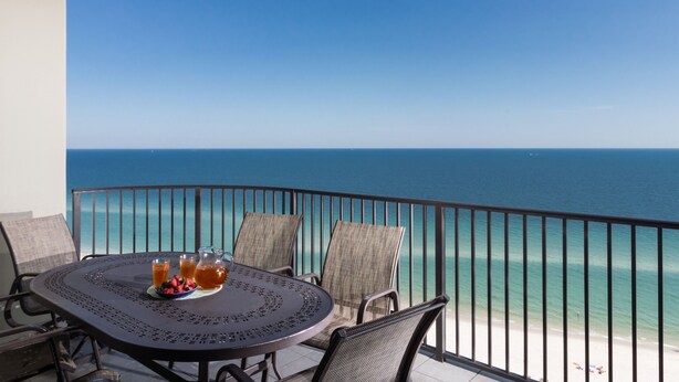 A round table with a metal frame, two wicker chairs, and a wicker bench. - Beach Front, Spacious, Clean and Comfortable (Orange Beach)