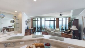 A modern kitchen with a large island, a dining area with a view, and a living room with a sofa and coffee table. - Beach Front, Spacious, Clean and Comfortable (Orange Beach)