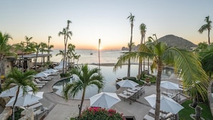Un resort con piscina, sillas de descanso, sombrillas y palmeras.