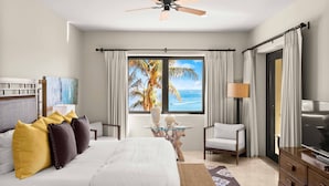 Habitación de hotel con cama, televisión, ventilador de techo, ventana con vista a palmeras y al océano, y una silla.