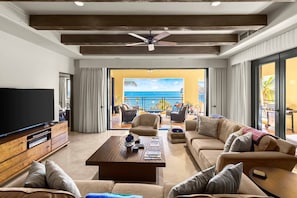 Relax in this stylish living room with a large flat-screen TV, comfortable seating, and ocean views from the balcony.
