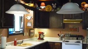 A kitchen with dark wooden cabinets, a white countertop, a red bowl, a mixer, and a stove. - Rushing Creek w/Mountain Views! Perfect Cabin for Family/Couples Getaways! (Nathrop)