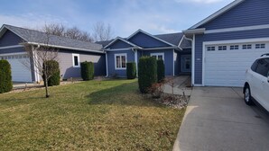 A residential house with a garage, a driveway, and a white SUV parked in front.
