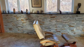 A room with a stone wall, a window with a view, and a chair.