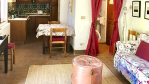 Une pièce chaleureuse avec un plafond en bois, un coin repas avec une table et des chaises, une cuisine avec des meubles en bois et un lit avec une literie à motifs floraux.