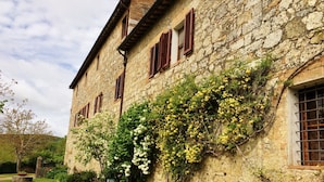 Un bâtiment en pierre doté de nombreuses fenêtres et d’un jardin à l’avant.