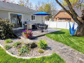 A patio with a grill, outdoor furniture, and a blue umbrella.