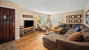 Ein Wohnzimmer mit Fernseher, Sofas, einem Couchtisch und einem Schild mit der Aufschrift 'BOATHOUSE'.