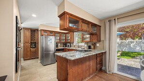 Eine Küche mit Holzausstattung, einem Edelstahlkühlschrank und einer großen Kochinsel mit Granitabdeckung.