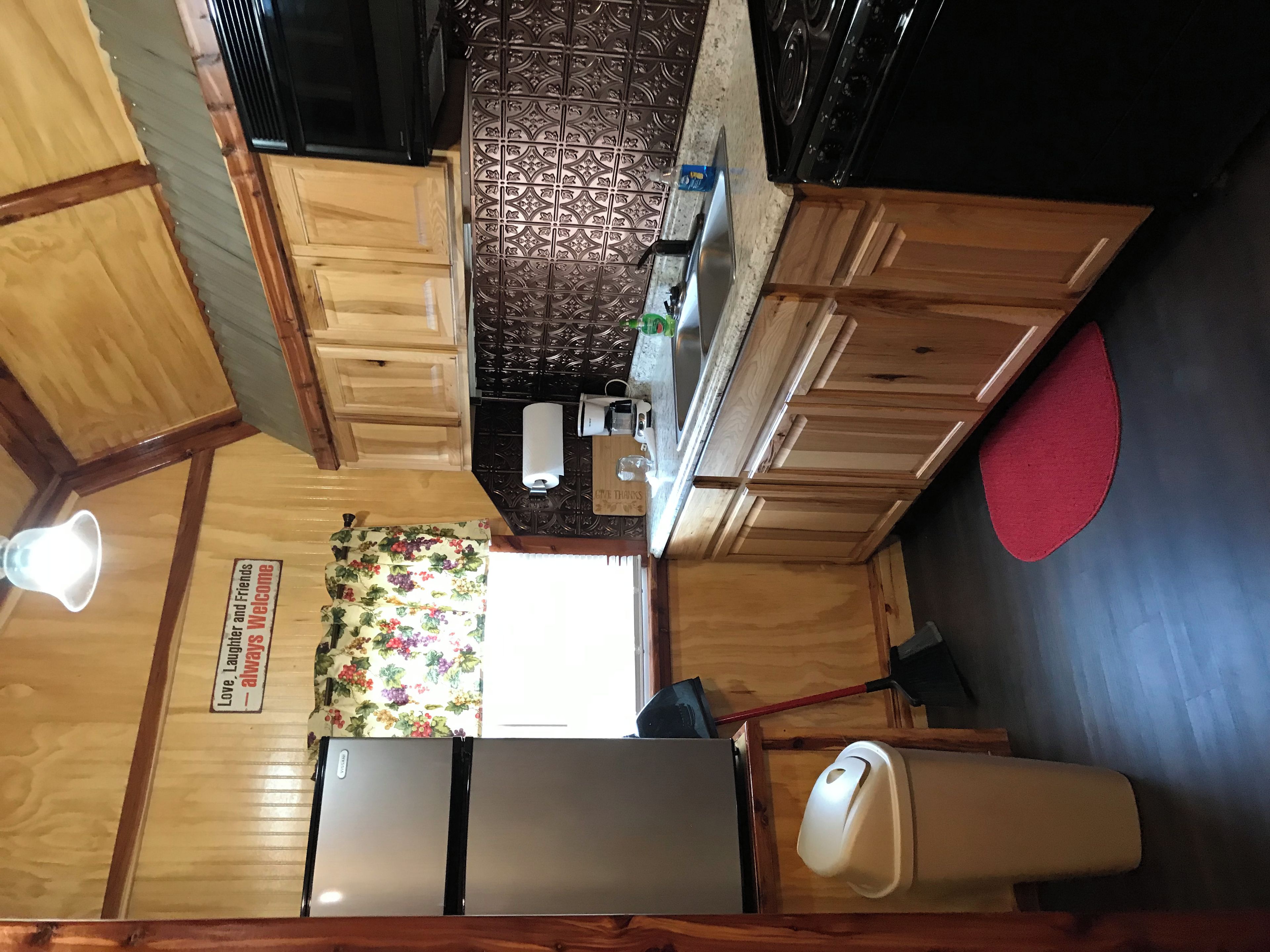 A compact kitchen with a wooden countertop, a sink, a coffee maker, and a patterned backsplash.