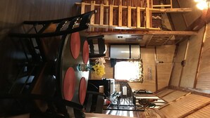 A dining area with a wooden table and chairs, a refrigerator, and a window with curtains. - Lovely secluded rustic cabin within waking distance of Rocky Top Winery . (Atwood)