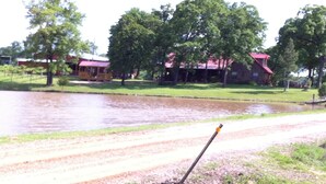 A rural landscape with a pond, a wooden dock, and a red-roofed building. - Lovely secluded rustic cabin within waking distance of Rocky Top Winery . (Atwood)