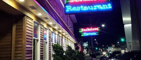 A Bucklews Restaurant with a neon sign, a brick pathway, and parked cars.