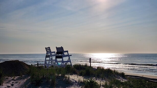 Ein Strand mit einer Reihe leerer Liegen, die zum Meer blicken.
