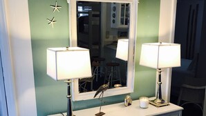A dresser with two lamps, a mirror, and decorative items against a green wall. - The Sea Palm, A Coastal Cottage Steps From The Beach!!! (Sunset Beach)
