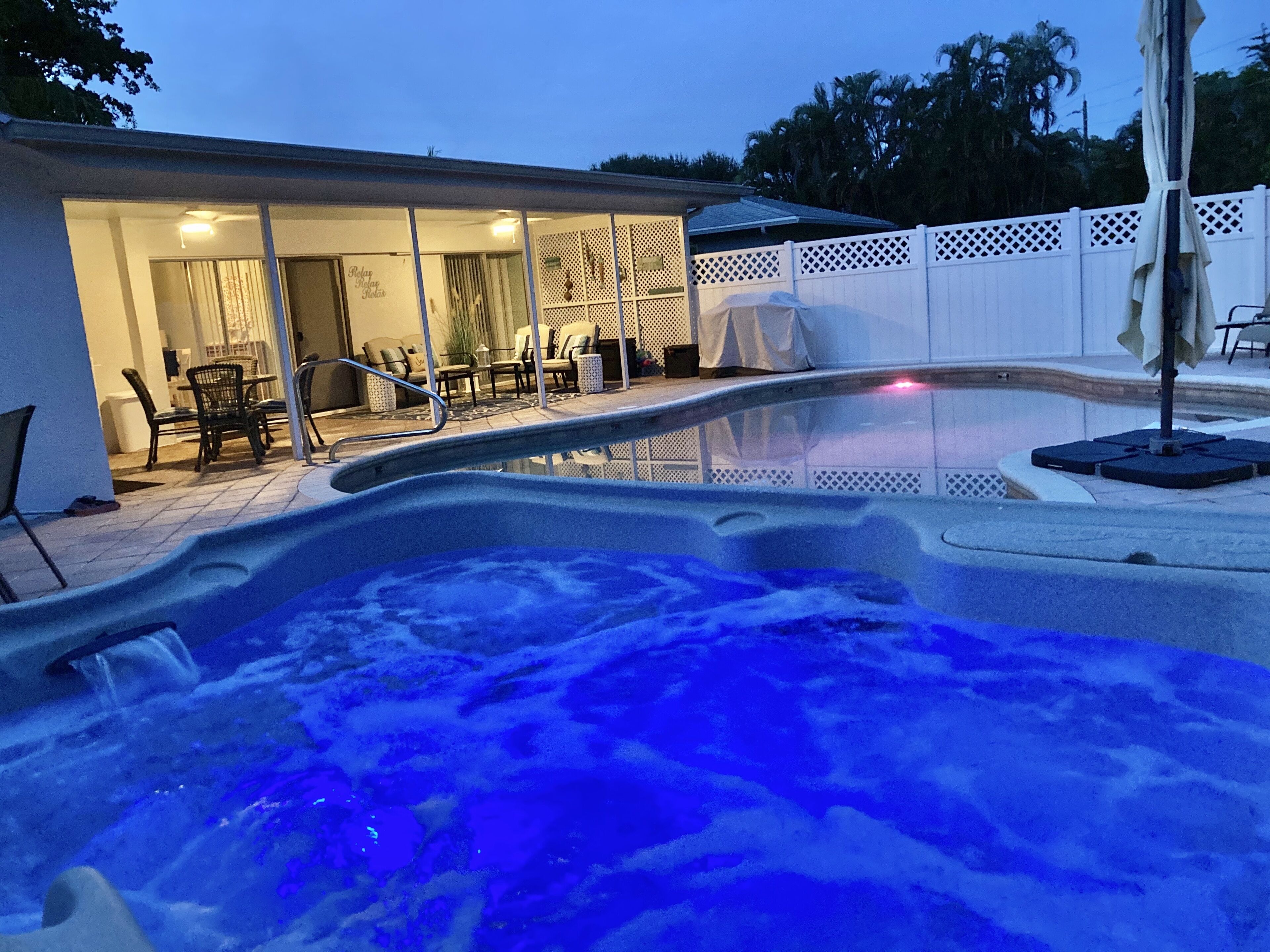 Un bain à remous avec vue sur un espace patio comprenant des meubles d’extérieur et un coin salon abrité.