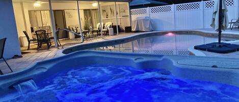 Un bain à remous avec vue sur un espace patio comprenant des meubles d’extérieur et un coin salon abrité.