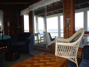 Ein gemütliches Blockhaus-Interieur mit Holzboden, einem gewebten Sessel, einem blauen Sofa und einem Tisch.