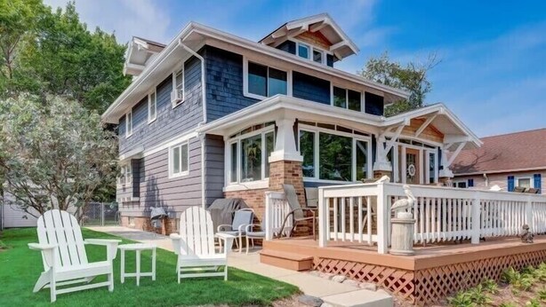 A two-story house with a covered porch, outdoor seating, and a well-maintained lawn. - Enjoy Beachfront Living With family!  (Racine)