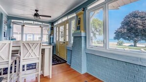 A room with a dining area, large windows, and a view of the outdoors. - Enjoy Beachfront Living With family!  (Racine)