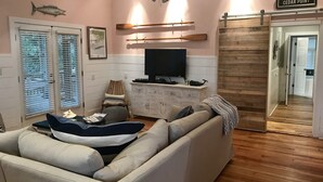 A living room with a large sofa, a television, and a ceiling fan. There are wooden walls and a sign that reads "CEDAR POINT".