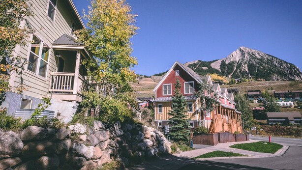 A residential area with houses, a stone wall, and a mountain in the background. - Winter Chalet, pet friendly, shuttle!
Leaves are changing!
Discounted rates! (Crested Butte)